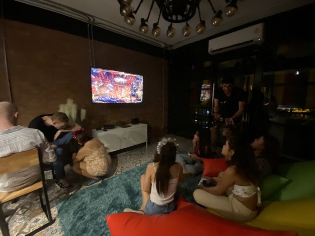 People playing video games on a television while seated on beanbags and carpet.