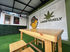 Green Family cannabis shop in Pai, Mae Hong Son, with a wooden table, green artificial grass, and sign.