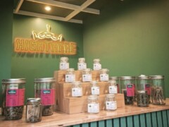 Interior of HIGHTHERE cannabis shop in Hua Hin, displaying jars of cannabis flower and smoking accessories. Neon sign visible.