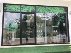 Exterior of Rolling Stoned Phuket dispensary in Chalong, Phuket, featuring glass storefront, cannabis leaf logo, and open hours.