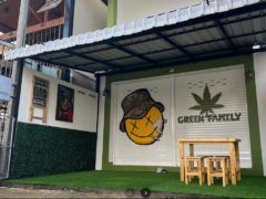 Exterior of Green Family cannabis shop in Pai, Mae Hong Son, Thailand, with logo and smiley face art.