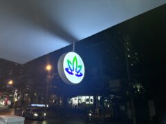 Sign for HighMed dispensary on Ekamai Road, Sukhumvit 63, Bangkok, with cannabis leaf logo, lit up at night.