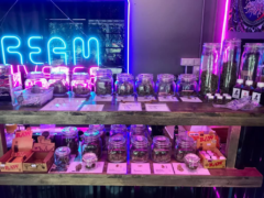Interior of Jakawan Shop in Rayong, Thailand, displaying cannabis flower in glass jars, neon lights and smoking accessories.