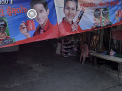 Street view of a shop in Nonthaburi, Thailand, with advertisements for coffee.