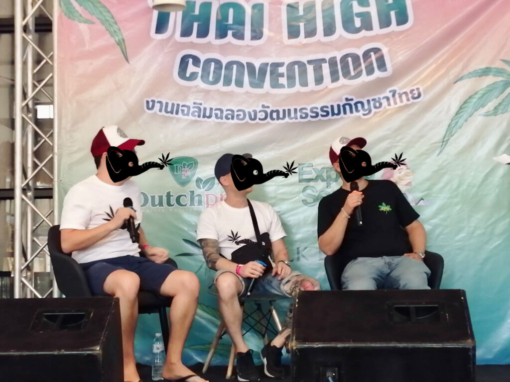 Three men on a stage with microphones, in front of a banner that says "Thai High Convention".
