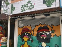 Signage for 7th Heaven Koh Chang 2 cannabis dispensary on White Sands Beach, with cannabis leaf logo and mural on shutters.