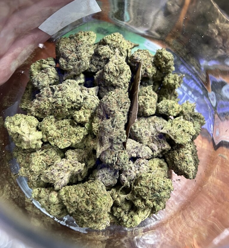 Close-up of cannabis nugs in a clear container.