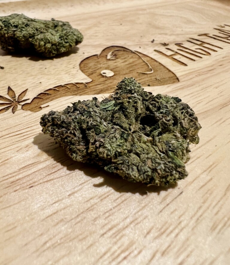 Two cannabis buds on a wooden tray.
