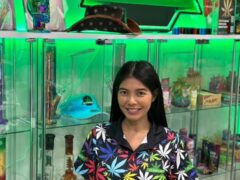 El Patron Dispensary in Hua Hin, Thailand, with woman smiling in cannabis leaf shirt and smoking accessories.