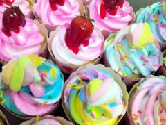 Cupcakes with pink, blue, and yellow frosting, strawberries, and marshmallows.
