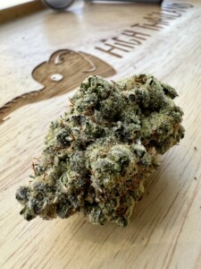 Close-up of a cannabis flower bud on a wooden surface.