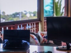 Laptop and monitor on a table, potentially at a cannabis cafe in Phuket.