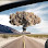 Atomic bomb explosion in a desert landscape, with a road in the foreground.