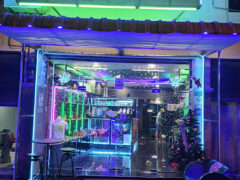 Exterior of FLOAT AWAY dispensary in Phitsanulok, Thailand, with neon lights, cannabis flower display, and smoking accessories.