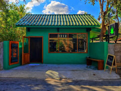 Exterior of Green House Pai in Mae Hi, Pai, showing a green cannabis shop with sign and open door, cannabis leaf logo.