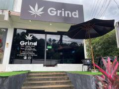 Exterior of Grind Phuket dispensary in หาดสุรินทร์, Phuket, Thailand, showing sign with cannabis leaf and open sign.