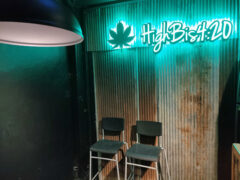 Interior of Highbis420 Lampang cannabis shop in Sop Tui, Thailand, with neon sign and two chairs.