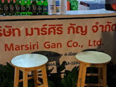 Marsiri Gan cannabis shop on Ubon-Trakarn Rd, Mueang Ubon Ratchathani, Thailand, with two stools, and cannabis for sale sign.