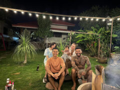 Group of people outdoors, string lights, at New Story Weed & Coffee in Ban Cha, Sing Buri.