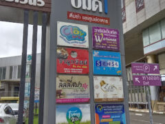 Sign for imd, Trang, Thailand, with various businesses including 