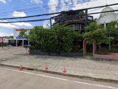 Exterior of The Social Cannabis Shop in Mueang Phitsanulok, Thailand, multi-story building and greenery.