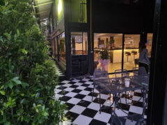 Exterior of The Weedery Dispensary in Bueng Kum, Bangkok, showing black and white checkered flooring and outdoor seating area.