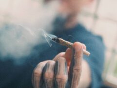 Hand holding lit cannabis joint. Weed smoking in Bangkok, Thailand.