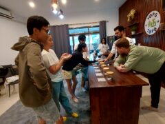 People in Top Genetics Dispensary, Chiang Mai, interacting near a table with cannabis products.