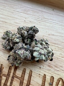 Close-up of several cannabis flower buds on a wooden surface.