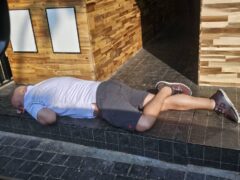 Man sleeping on the steps outside Harmony Herb cannabis dispensary, Walking Street, Pattaya, Thailand.