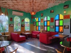 Interior of Chief Weed Dispensary in Mae Rim, Chiang Mai, featuring seating and colorful stained glass windows.
