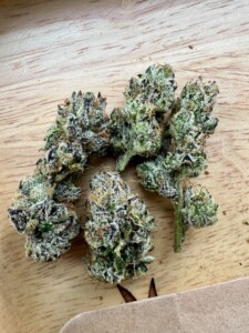 Pile of cannabis buds on a wooden surface.