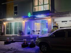 Exterior of Bongka.BKR dispensary in Lat Phrao, Bangkok, with neon cannabis leaf sign and car parked in front.