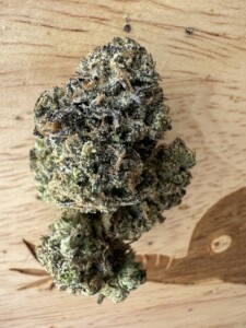 Close-up of a cannabis bud on a wooden surface.