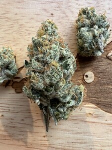 Three cannabis flower buds on wood.
