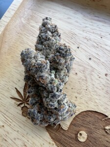 Cannabis flower bud on a carved wooden tray.