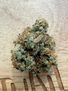 Close-up of a cannabis flower bud on a wooden surface.