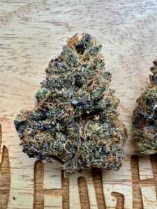 Close-up of a colorful cannabis flower bud on a wooden surface.