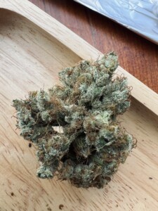 Cannabis flower bud on a wooden tray.