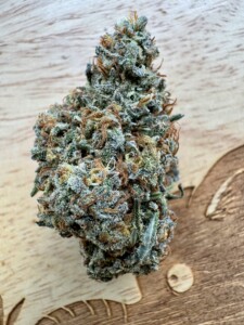 Close-up of a cannabis flower bud on a wooden surface.