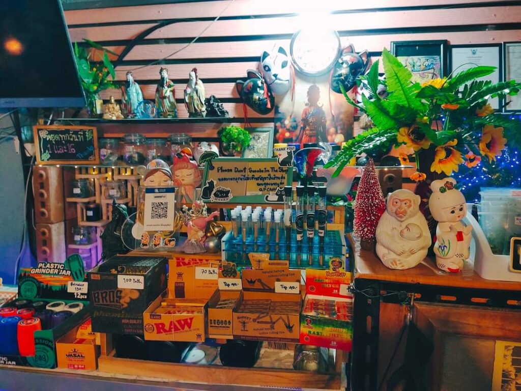 Shop display with rolling papers, grinder jars, figurines, and decorative objects.