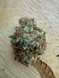 Cannabis flower bud on wood surface.
