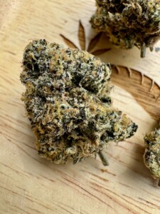 Close-up of a cannabis bud on a wooden surface.