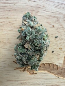 Close-up of a cannabis flower bud on a wooden surface.