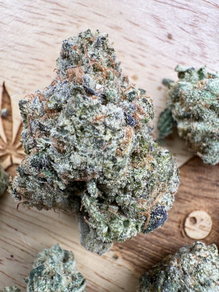 Close-up of a cannabis bud on a wooden surface.