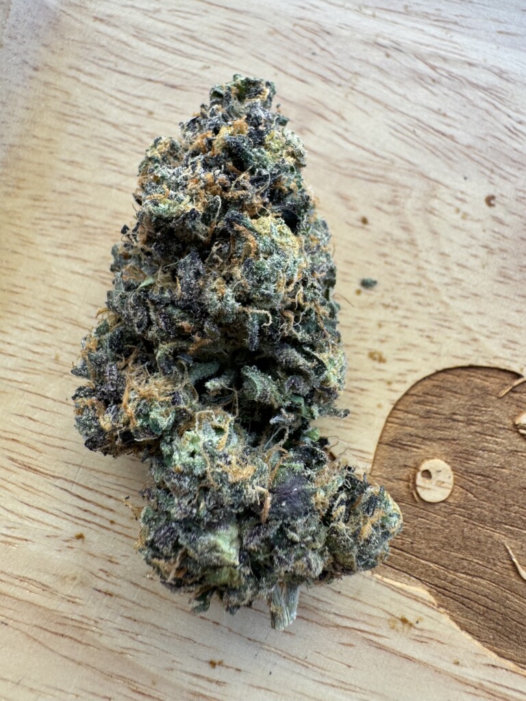 Cannabis flower bud on a wooden surface.