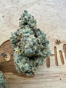 Close-up of a frosty cannabis flower bud on a wooden surface.