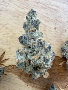 Cannabis bud with trichomes on a wood surface.