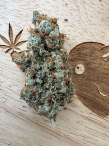A close-up of a cannabis bud on a wooden surface.