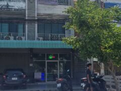 Two-story building with a cannabis shop, motorcycles parked outside, and a person walking.
